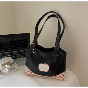 Close-up of black tote bag with cute apple print and polka dot corners on white desk