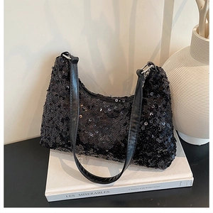 Detail of shimmering black sequin handbag resting on a book with silver metal buckles
