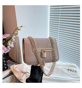 Detail of nude crocodile texture bag with gold heart padlock and dual chain straps