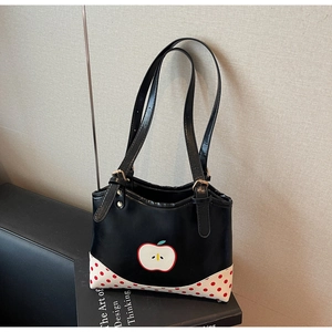 Dettaglio borsa shopper nera con stampa mela, bordo a pois e spalline con fibbia regolabile