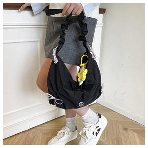 Detail of black pleated shoulder bag with purple bow and yellow flower pendant