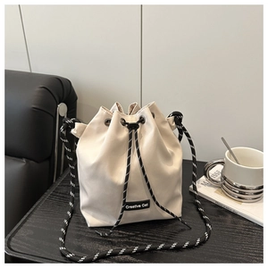 Détail du sac seau en nylon crème avec bandoulière tressée et étiquette Creative Cat