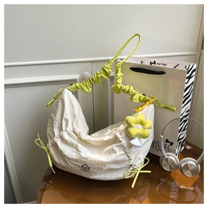 Detail of white ruched shoulder bag with lime green strap and yellow flower charm