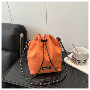 Détail d'un sac seau en nylon orange avec sangle tissée et cordon de serrage
