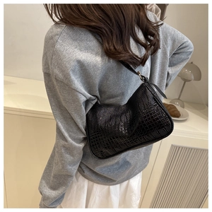 Detail shot of the glossy black crocodile pattern hobo bag with a slim shoulder strap