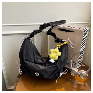 Detail of black nylon dumpling bag with purple bow and yellow flower pendant decoration