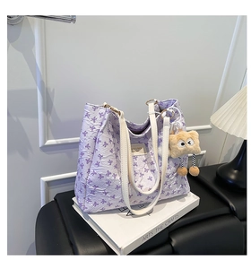 Détail du sac cabas violet avec imprimés nœuds et breloque peluche sur livres