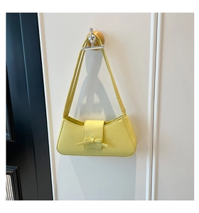 Primer plano del bolso de hombro amarillo brillante con textura de grano y lazo detalle