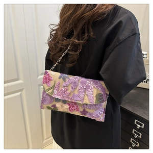 Macro detail of hand-embroidered floral sequins and chain strap on the flap bag