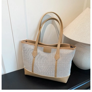 Minimalist canvas tote bag with brown faux leather trim on a sleek black table