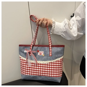 Detail der roten Karo-Schleife und Spitze an einer grauen Canvas-Tasche mit Kirsch-Patch