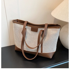 Detail of premium canvas tote bag with brown leather trim in a cozy warm lighting setup