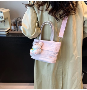 Detail der rosa plissierten Oxford-Handtasche mit Plüschbären-Anhänger und Stickerei