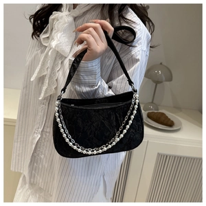 Detail of black jacquard shoulder bag featuring elegant pearl chains and metallic straps