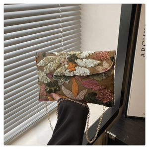 Close-up of handmade floral embroidery and sequins on brown chain crossbody bag