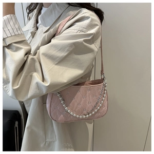 Detailed embroidery bow and pearl chain on a pink quilted leather shoulder bag