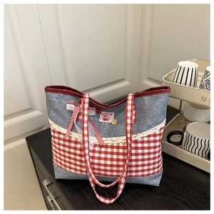 Detail der Denim-Tasche mit Karomuster, Spitzenkante und einer dekorativen Seidenschleife
