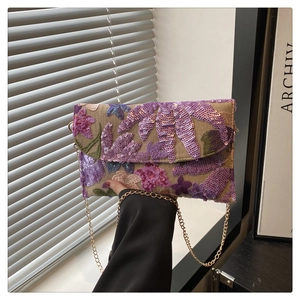 Detailed close-up of colorful floral sequin embroidery and gold chain on beige clutch