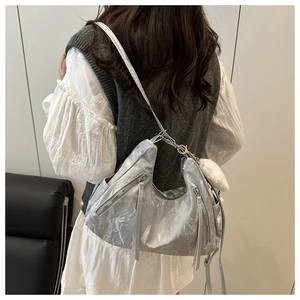 Detail of silver metallic hobo bag featuring crinkled texture and white fuzzy charm