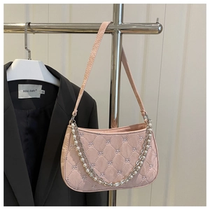 Detail of pink quilted baguette bag with pearl chain and bow pattern texture