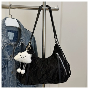 Close-up of black hobo bag with pleated texture, silver zippers and plush cloud charm
