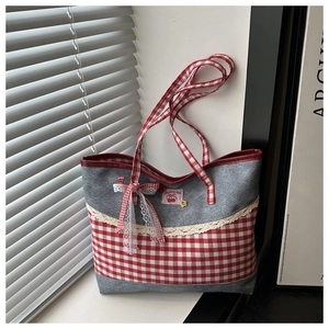 Detailansicht der grauen Denim-Tasche mit roter Karoschleife und Spitzenverzierung