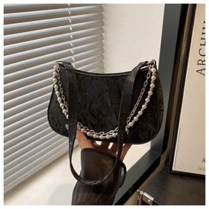 Detail of black quilted leather shoulder bag with silver chain and white pearl strap accents