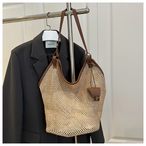 Détail d'un sac cabas en paille tressée avec anses en cuir marron et pendentif décoratif