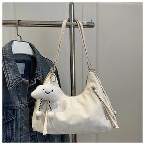 Detail of creamy white hobo bag with textured leather and a cute cloud plush charm