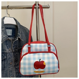 Detail of blue and white checkered handbag with red apple print and zipper front pocket