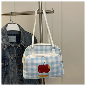 Detail of blue and white plaid shoulder bag featuring a red apple print and front zipper pocket