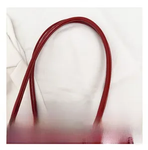 Close-up of a glossy burgundy baguette bag with smooth shoulder strap details