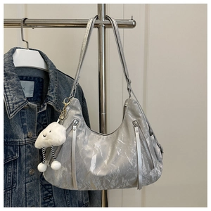 Detail of silver metallic hobo bag with fringe zippers and plush cloud pendant
