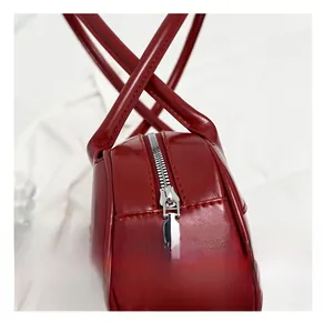 Detail view of smooth silver metal zipper and lychee texture on red leather baguette bag