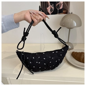 Detail of black half-moon shoulder bag with white bow embroidery and knotted rope strap