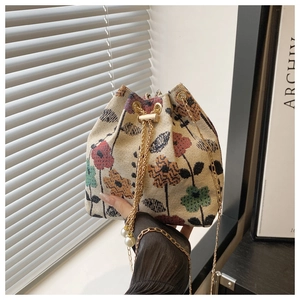 Detail of floral tapestry bucket bag with gold chain strap and pearl charms