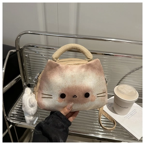 Detail einer süßen Plüschtasche in Katzenform mit Stickerei und flauschigem Bommel