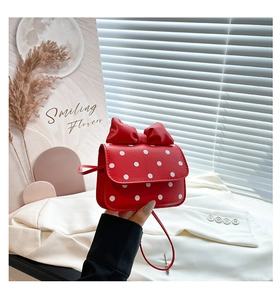 Detail of red polka dot mini bag with oversized bow and long crossbody strap