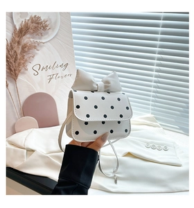 Close-up of white polka dot crossbody bag featuring a large decorative bow detail