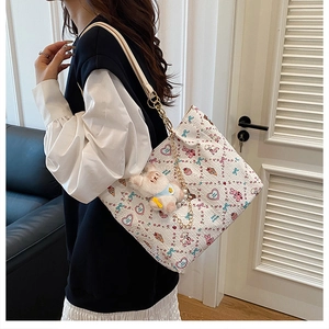 Detail of white tote bag with pink rabbit prints, gold chain strap and plush charm