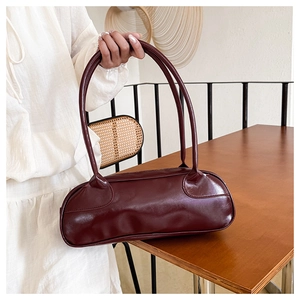 Detailed view of the deep burgundy baguette bag with a glossy finish and curved handle