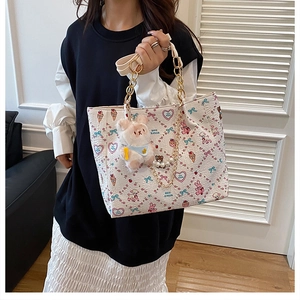 Detail of white tote bag with cartoon print, gold chain, pearls and rabbit charm
