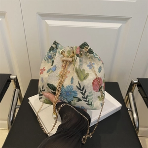 Floral jacquard bucket bag with drawstring closure, gold chain, and pearl pendant detail