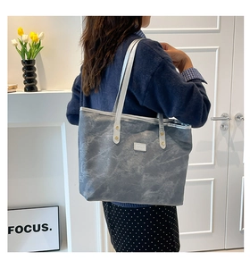 Detail of grey marble pattern tote bag with white leather handle and gold rivets