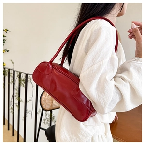 Detail view of a vintage dark red baguette bag showing shiny leather and double straps