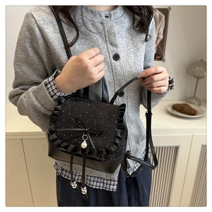 Detail of black mini backpack with lace frills, floral pattern and pearl pendant accent