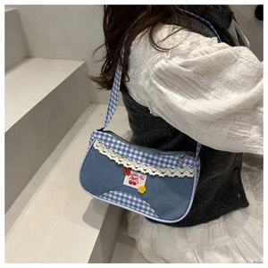 Close-up of blue plaid denim shoulder bag featuring lace edges and cherry embroidery
