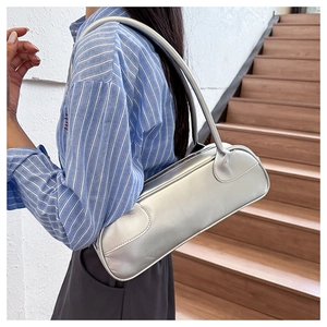 Side view of a silver baguette bag with a sleek metallic finish on a female model