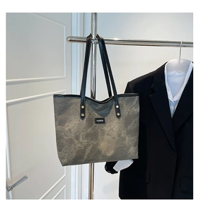 Dettaglio della borsa tote color talpa con trama marmorea e manici in pelle nera