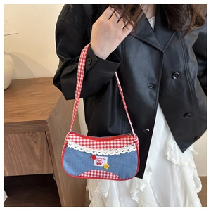 Detail shot of the denim shoulder bag showing cherry embroidery and red checkered strap
